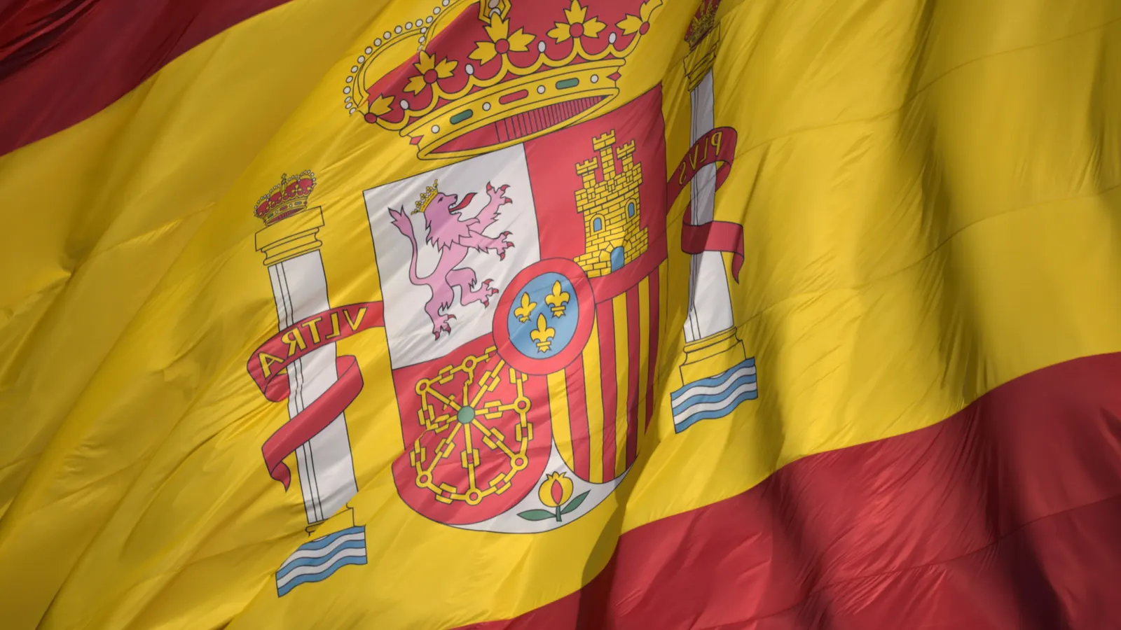 Primer plano del escudo de España sobre la franja amarilla de la bandera, entre las franjas rojas