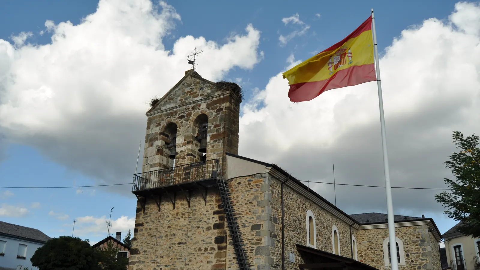 Un mástil con la bandera de España junto a la iglesia de Riello, en León