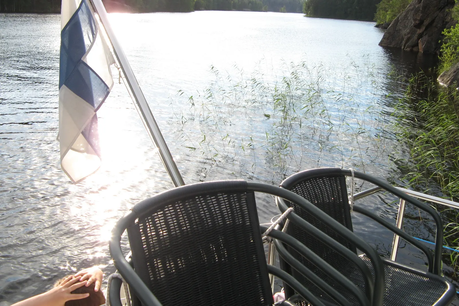 Suomen lippu veneen perässä järvellä ilta-auringossa