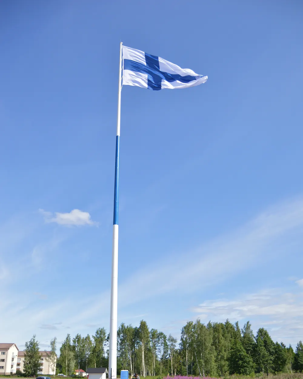 Suomen lippu erittäin korkeassa lipputangossa sinistä taivasta vasten