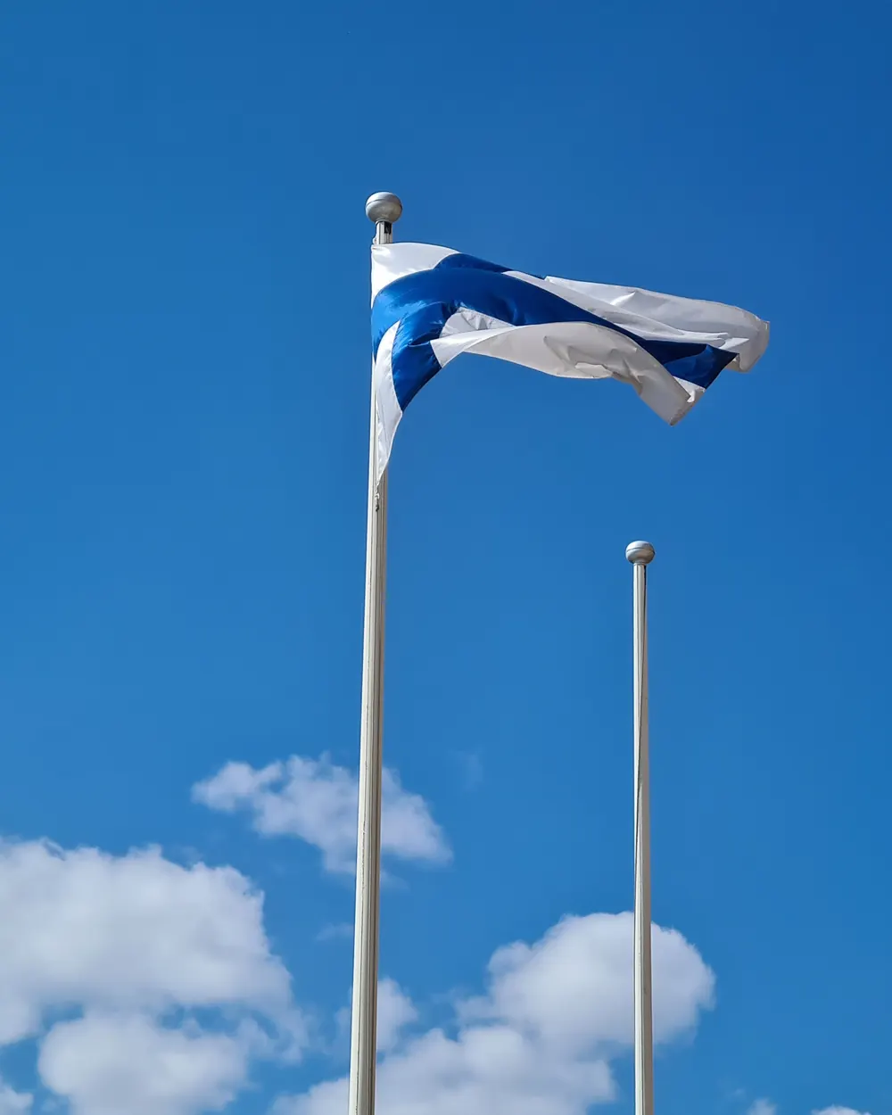 Suomen lippu valkoisessa lippusalossa sinistä taivasta vasten