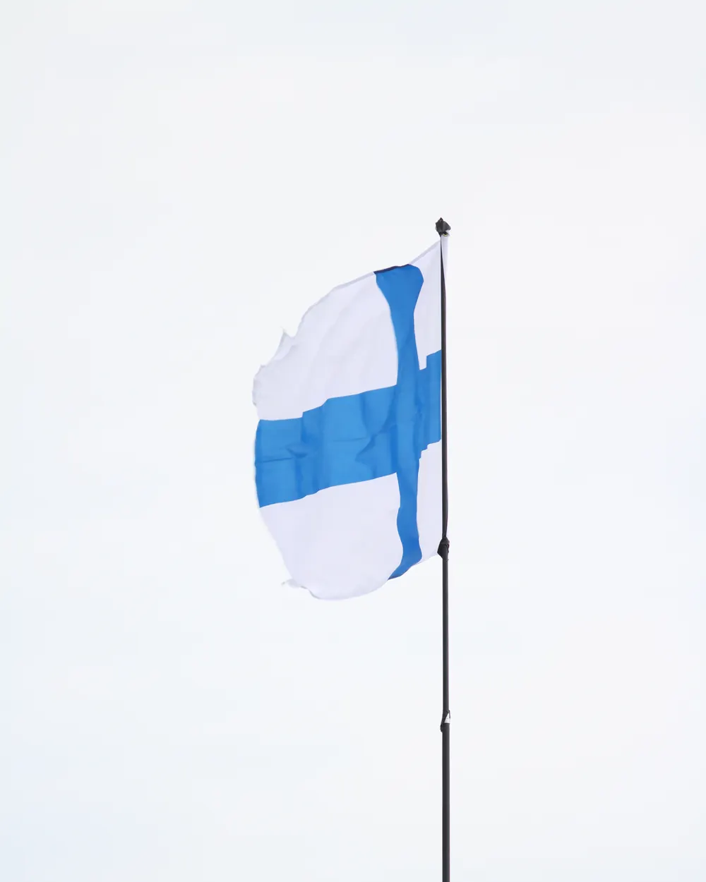 Suomen lippu suorana kovassa tuulessa ohuessa salossa