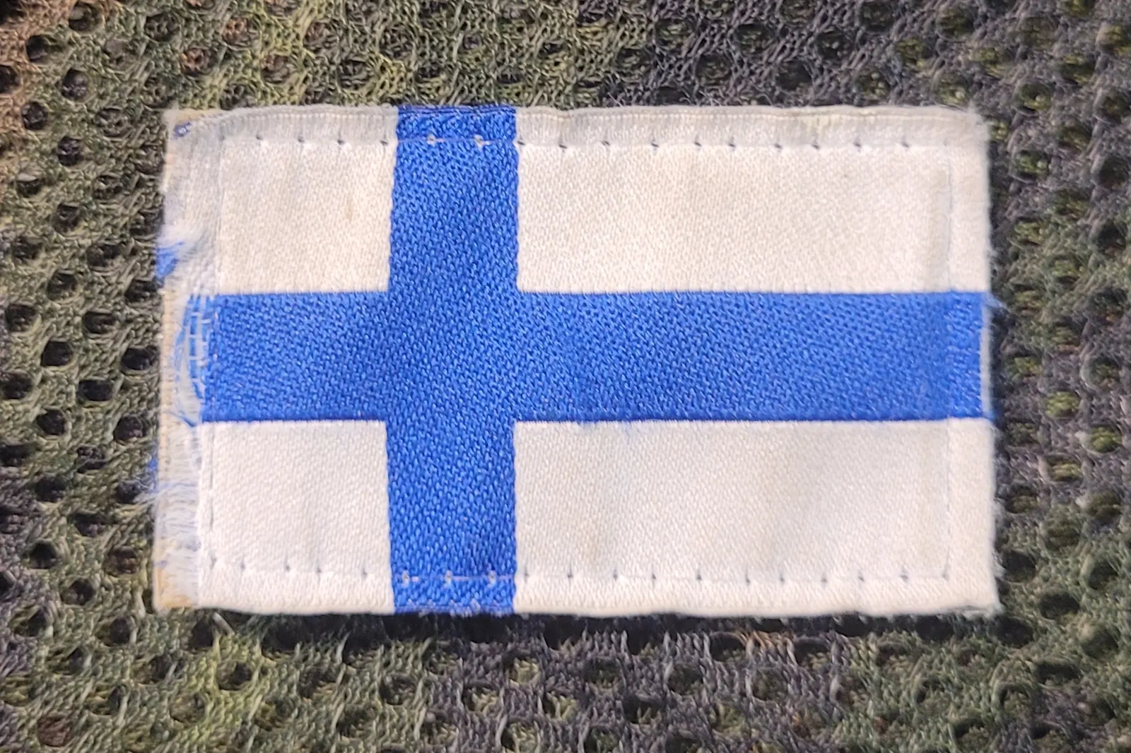 Ommeltu kangasmerkki, jossa on Suomen lippu