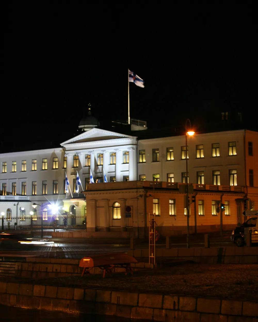 Presidentinlinna valaistuna illalla ja presidentin lippu katolla