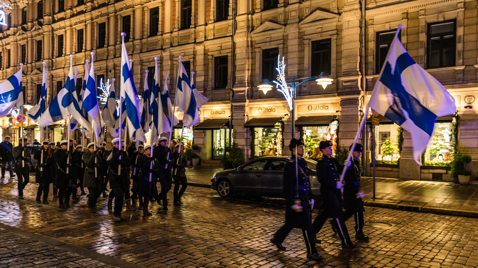 Opiskelijoiden soihtukulkue kantaa Suomen lippuja kadulla itsenäisyyspäivän iltana