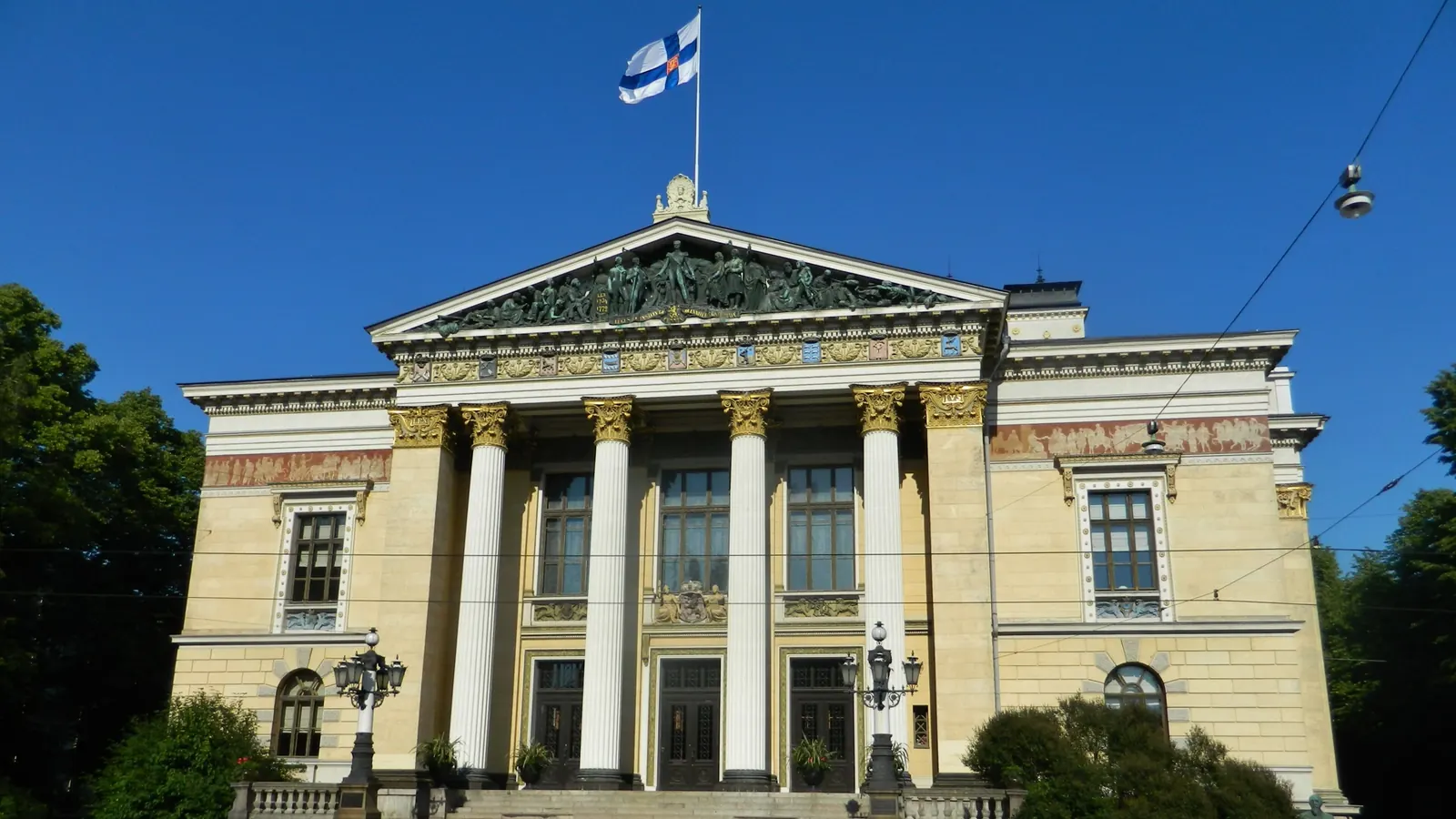 Säätytalo Helsingissä ja Suomen lippu katolla kirkkaana kesäpäivänä