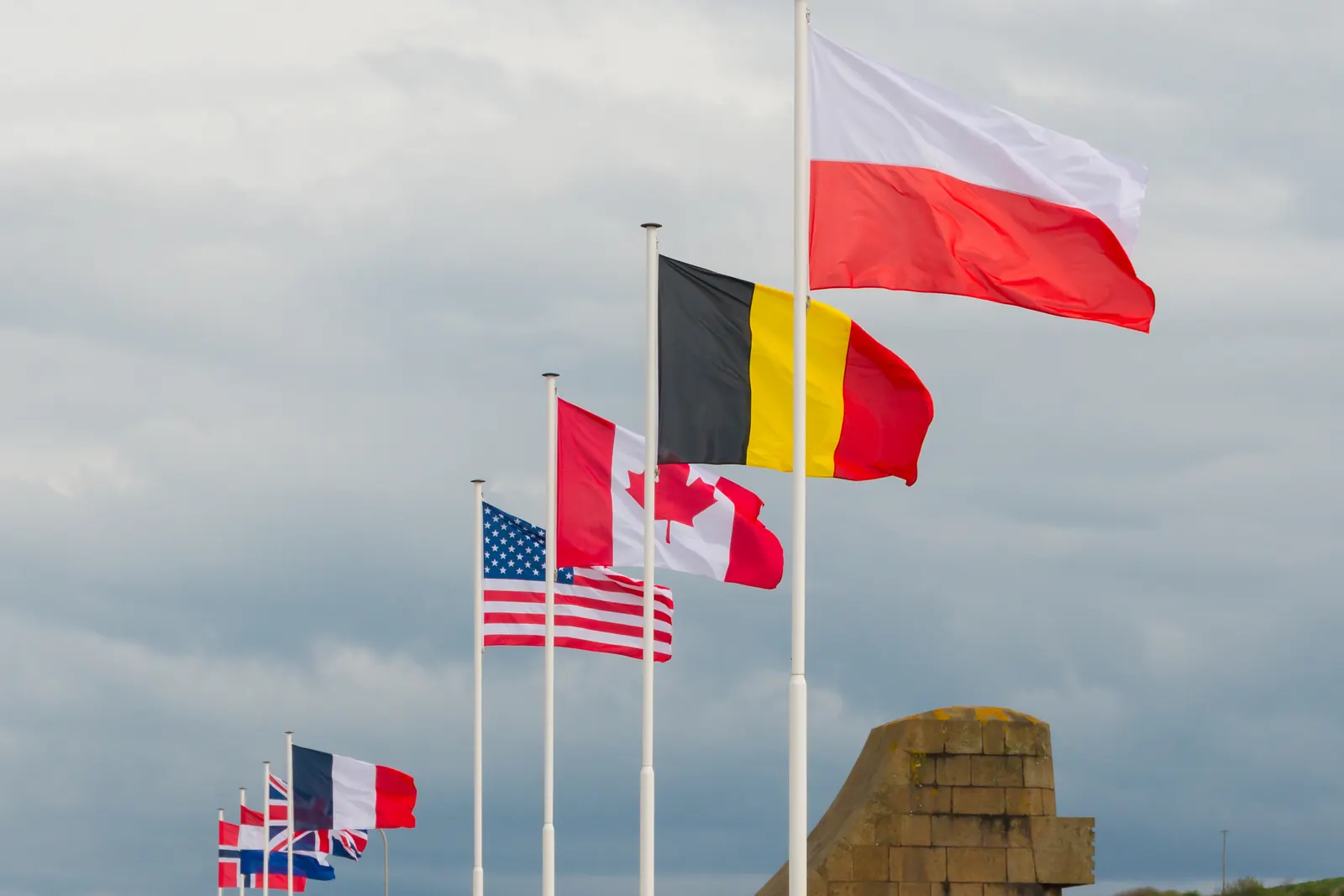 Drapeaux de pays alliés, dont la Pologne, la Belgique, le Canada et les États-Unis, à des mâts près d’Omaha Beach