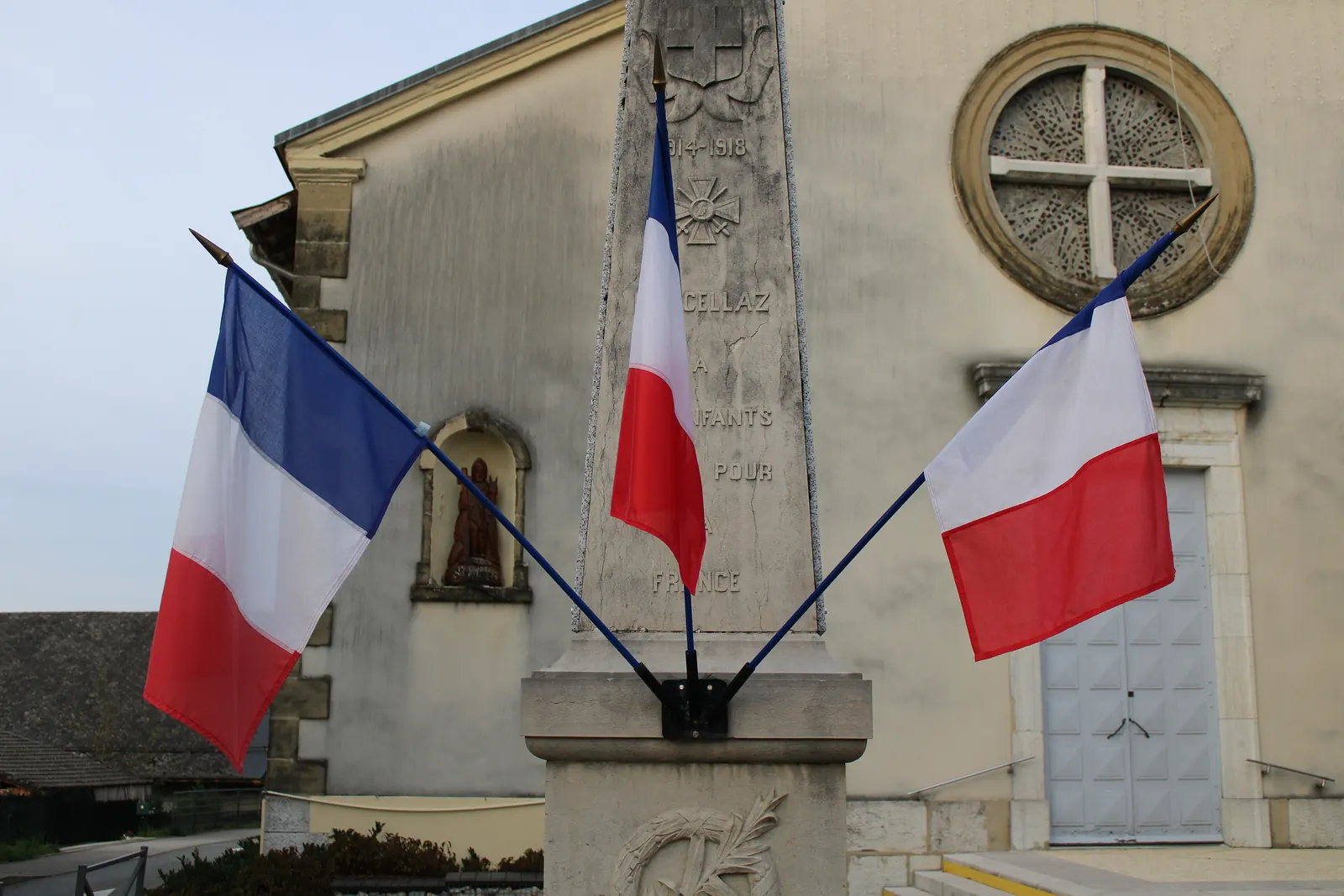 Trois drapeaux tricolores fixés au monument aux morts de Marcellaz-Albanais