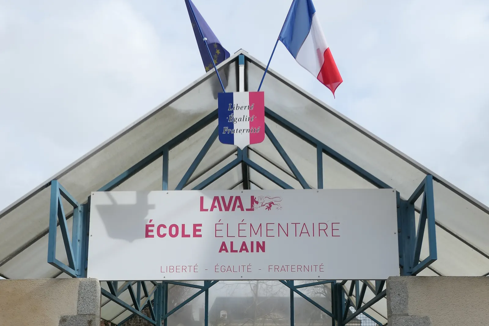 Entrée d’une école élémentaire à Laval avec le drapeau français et le drapeau européen
