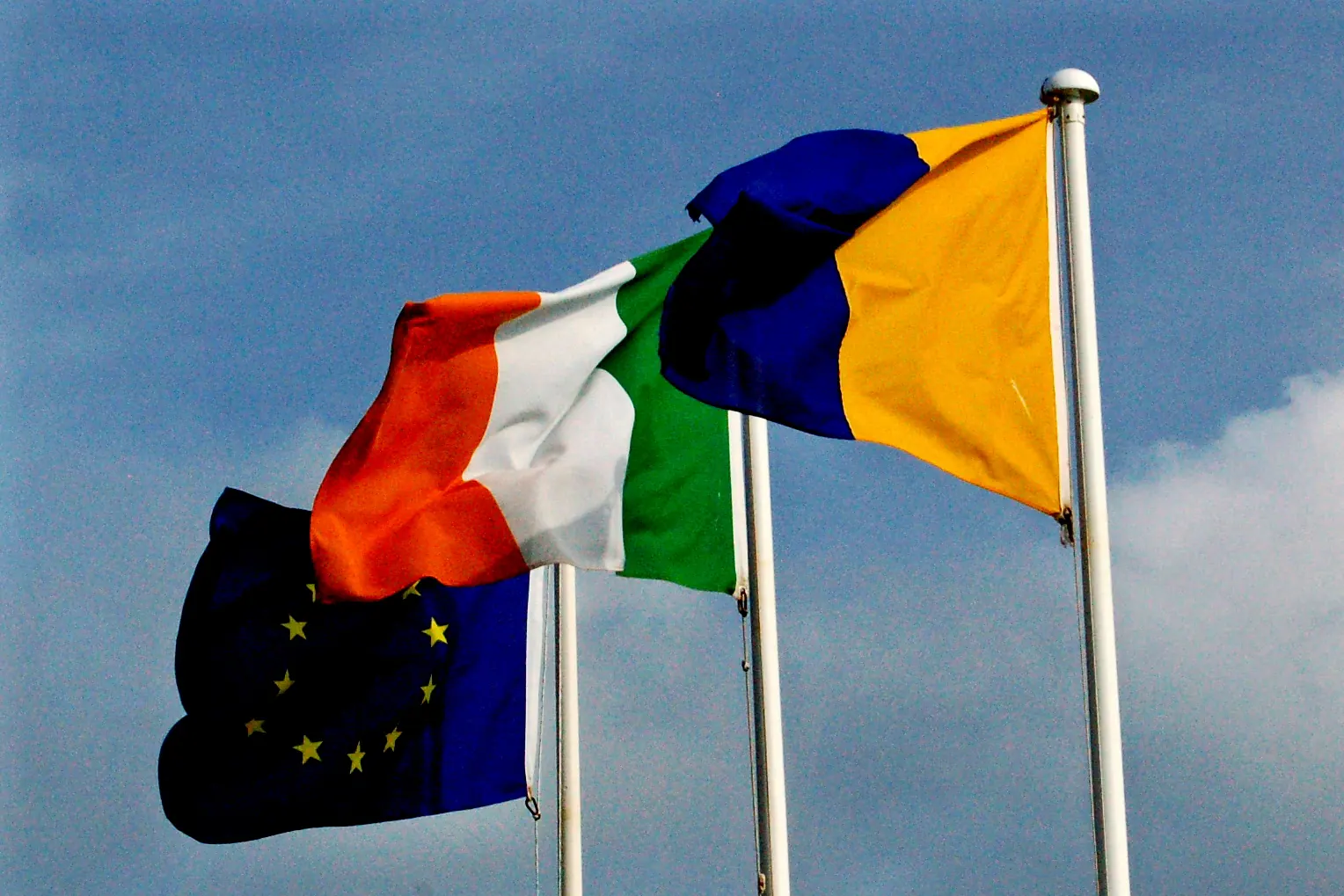 The flags of the European Union, Ireland and County Clare flying at the Cliffs of Moher, the EU flag on the left