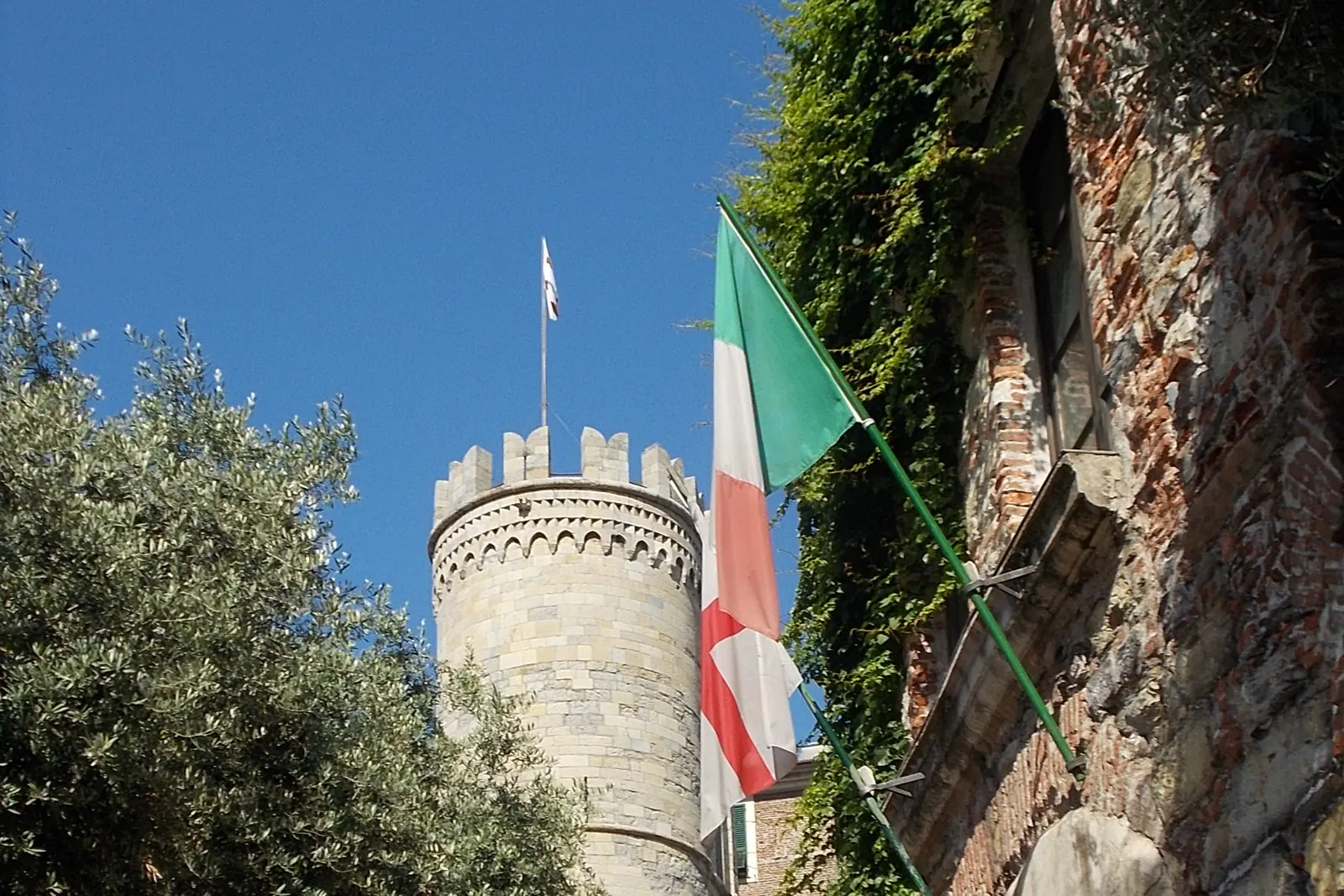 Il Tricolore e la bandiera di Genova presso la casa di Cristoforo Colombo, con la torre di Porta Soprana