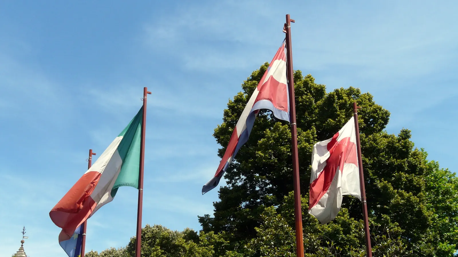 Il Tricolore, la bandiera di Ivrea e altre bandiere su pennoni in corso Cavour, a Ivrea