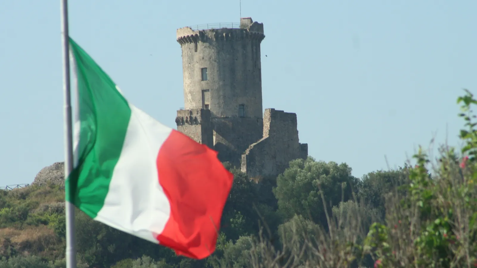 Il Tricolore spiegato dal vento forte davanti alla torre di Velia
