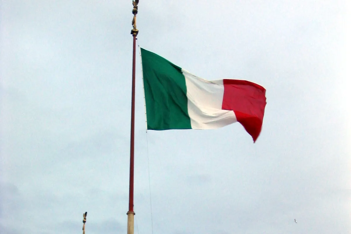 Il Tricolore in cima a un pennone del Vittoriano, sopra la balaustra e una statua