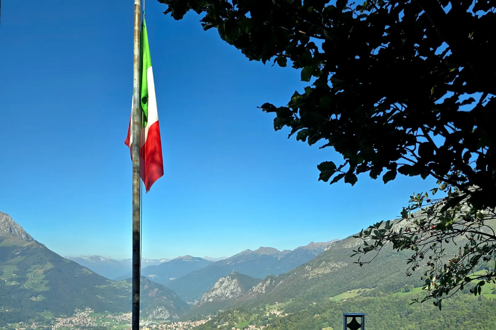 Un pennone con il Tricolore in vetta allo Zucco della Croce, con le montagne e la valle sullo sfondo