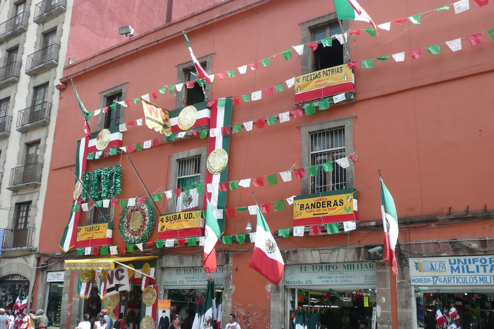 La fachada de una tienda adornada con banderas, guirnaldas y papel picado verde, blanco y rojo en septiembre