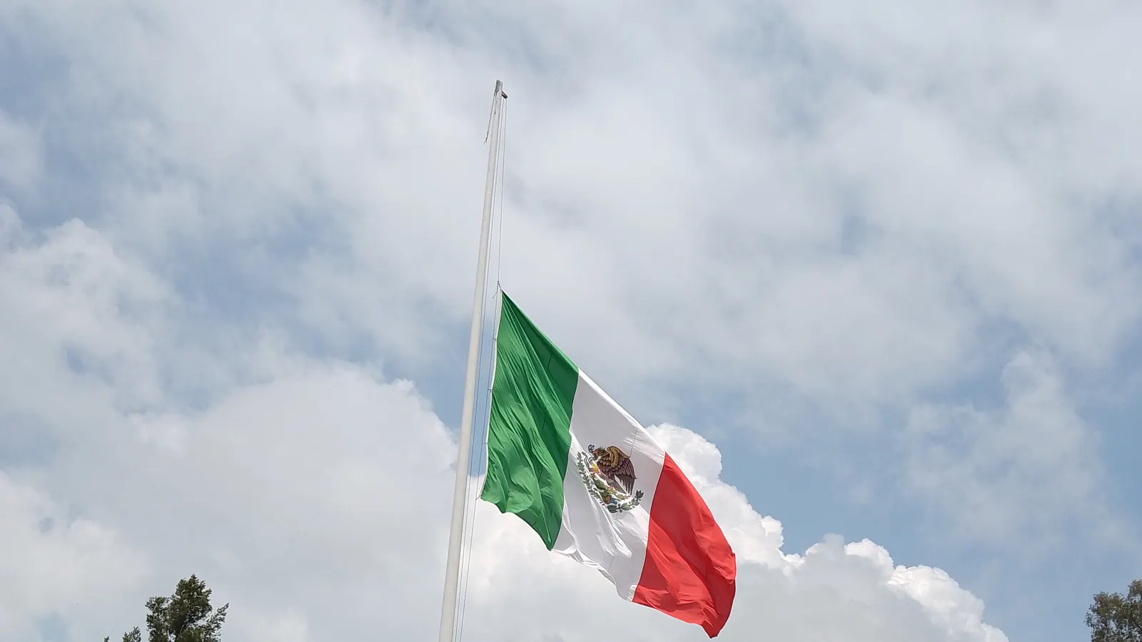 La Bandera Nacional a media asta sobre un monumento, con el cielo nublado