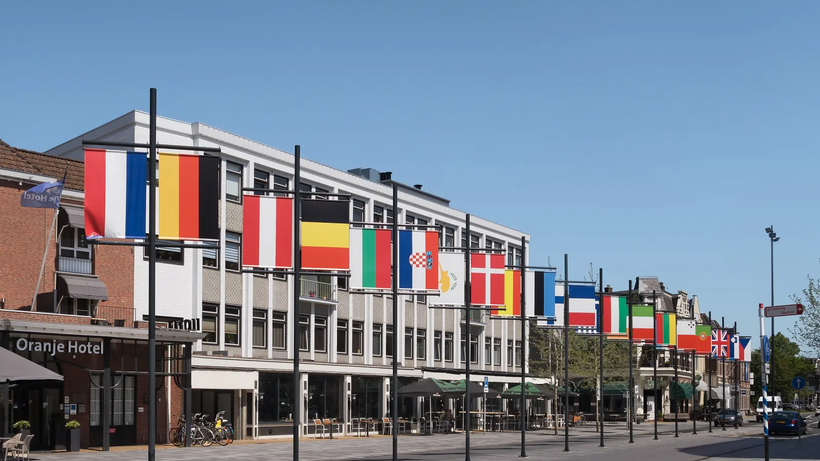 Een rij masten met de vlaggen van de EU-lidstaten langs de Stationsweg in Leeuwarden