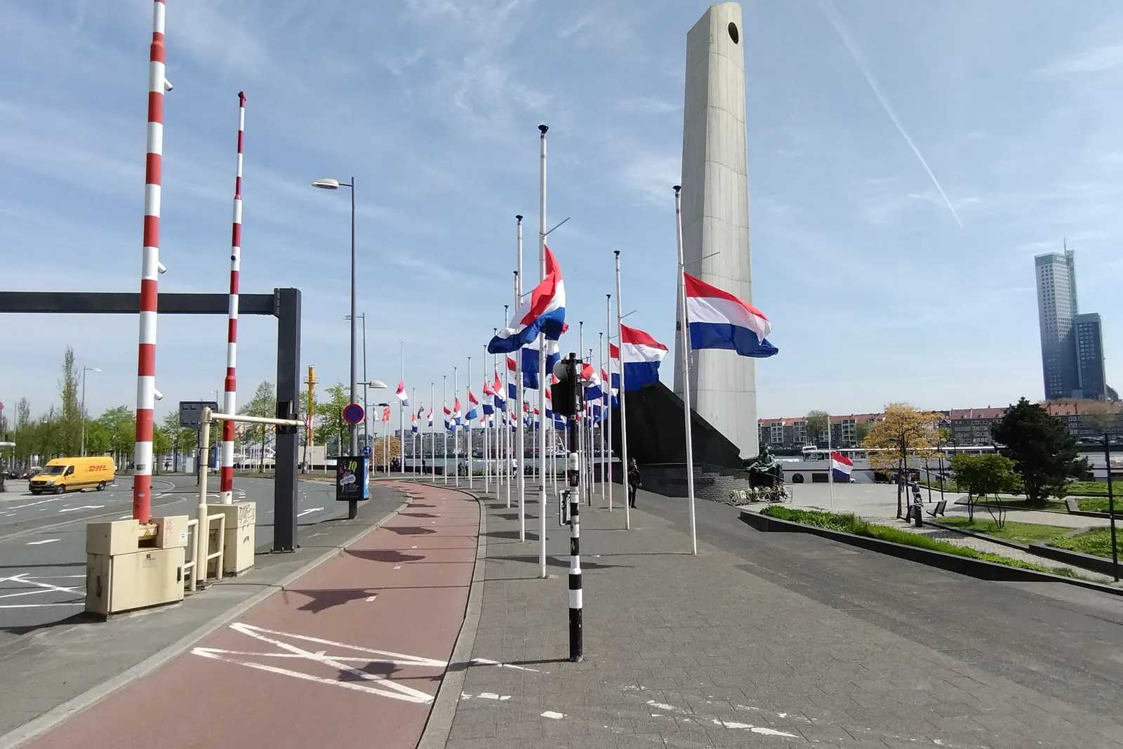 Een lange rij Nederlandse vlaggen halfstok bij het monument De Boeg in Rotterdam