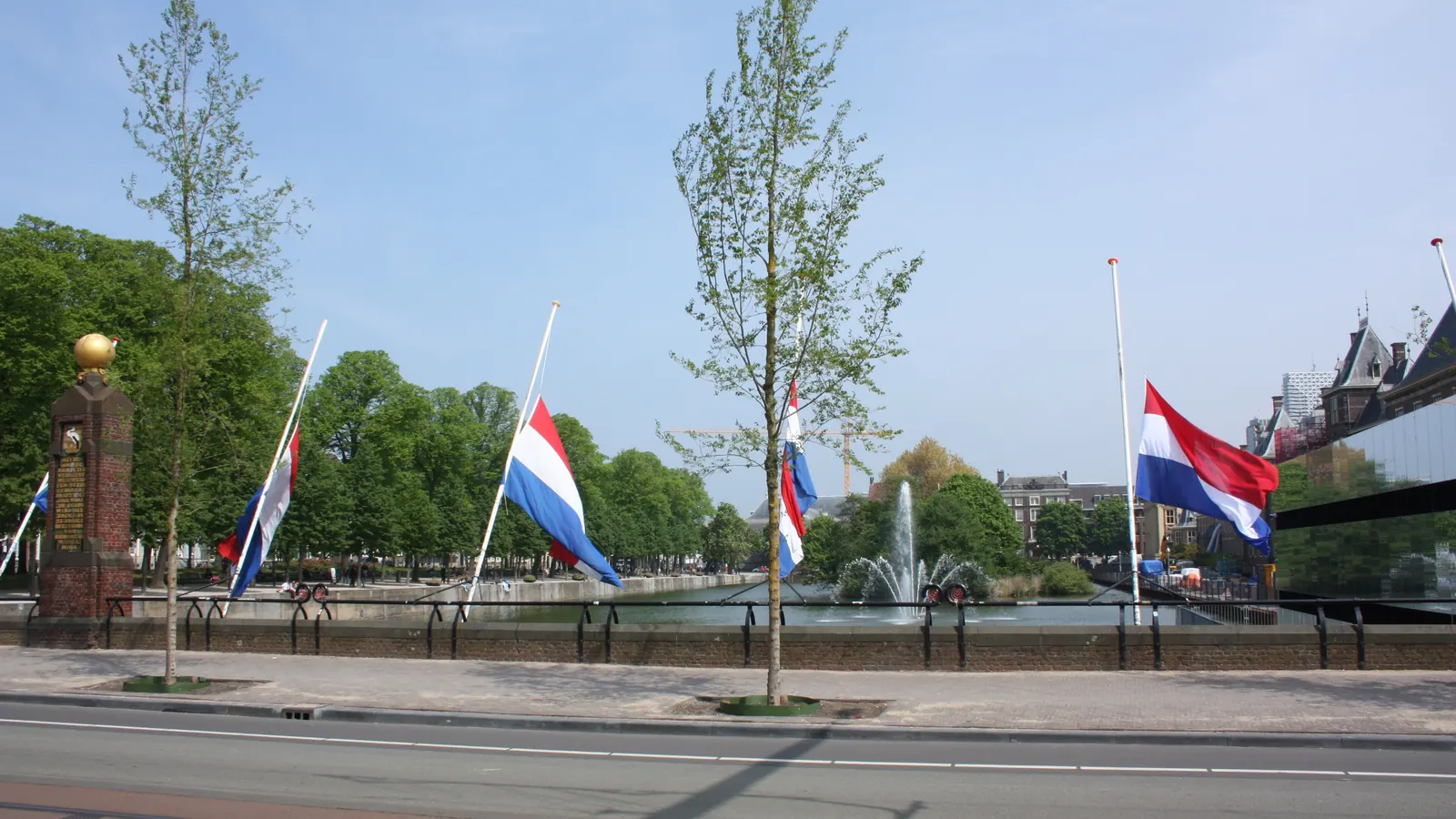Nederlandse vlaggen halfstok aan masten langs de Hofvijver in Den Haag