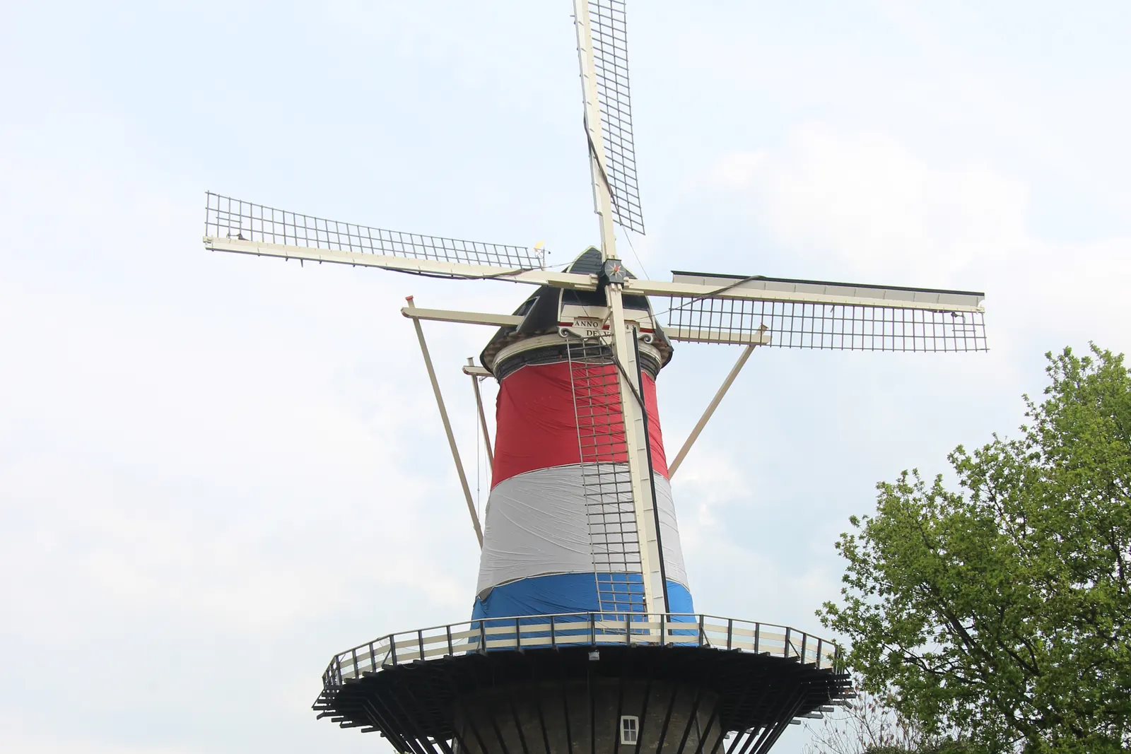 Molen De Valk in Leiden, beschilderd in rood, wit en blauw, boven een gracht vol mensen