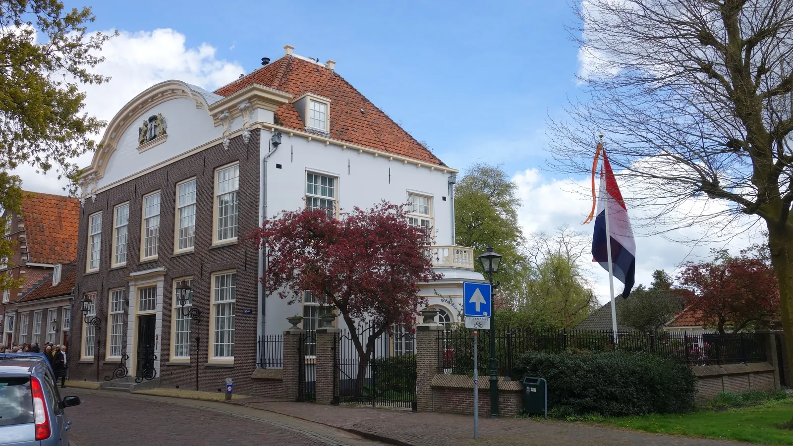 Een statig wit huis in Monnickendam met de Nederlandse vlag aan een mast voor de deur