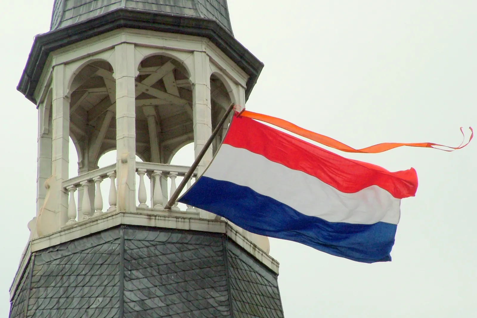 De Nederlandse vlag met een oranje wimpel aan de kerktoren van Silvolde