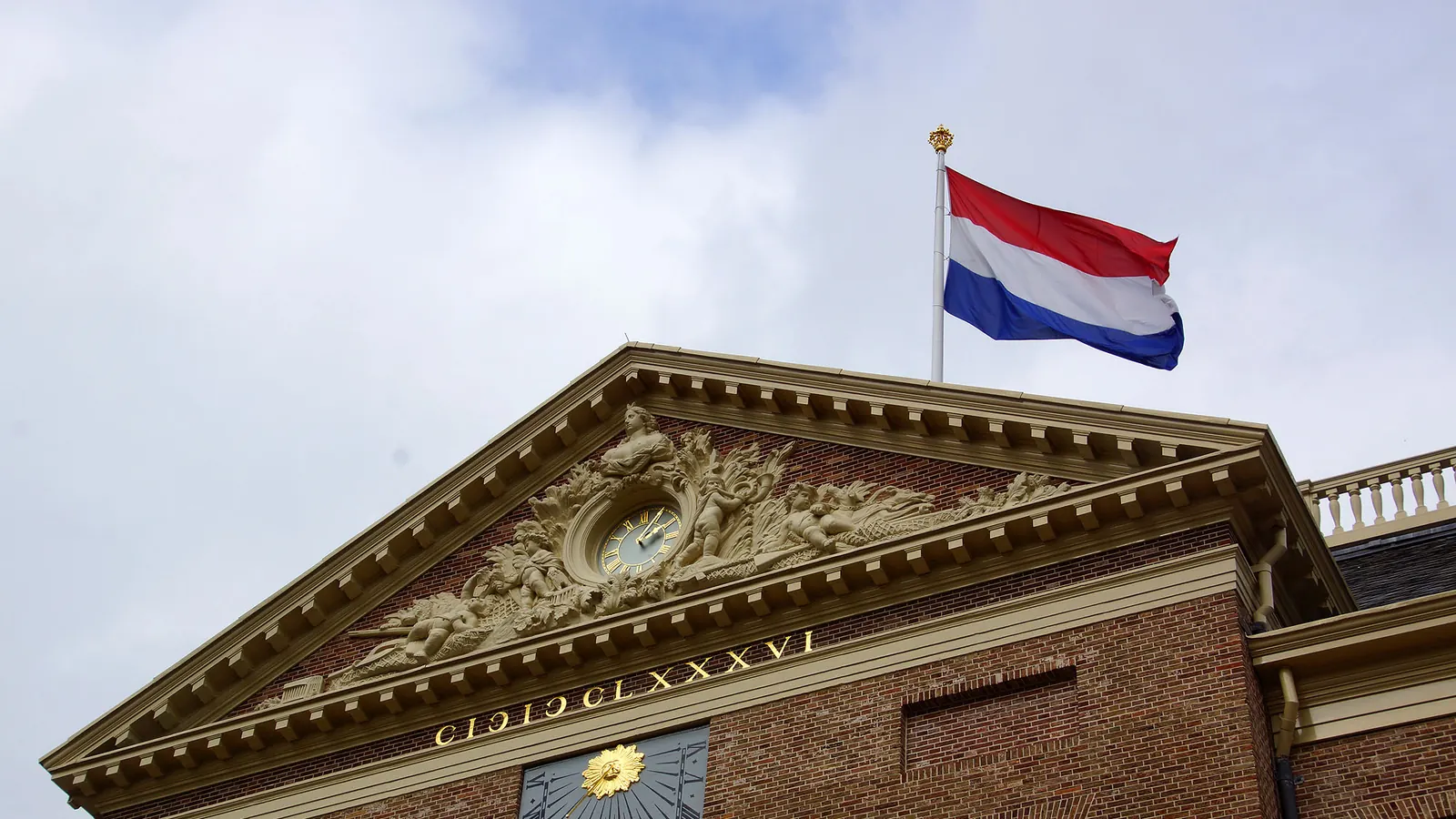 De Nederlandse vlag aan een mast boven het fronton van Paleis Het Loo