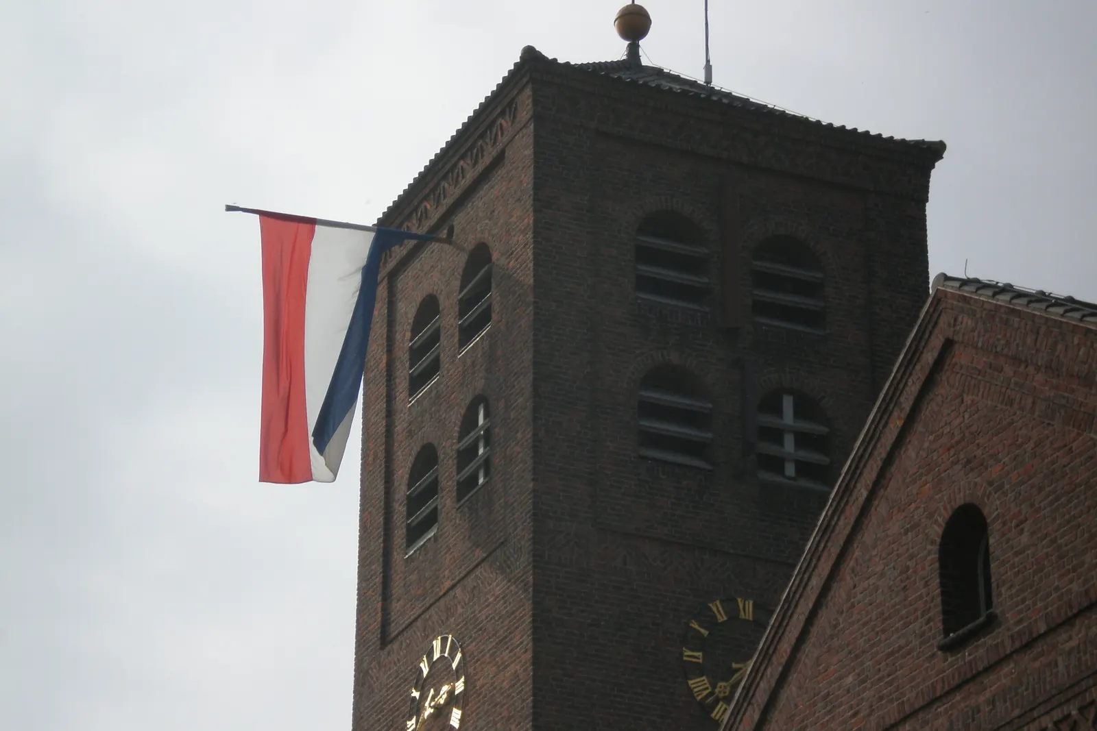 Een grote Nederlandse vlag aan een stok aan de bakstenen kerktoren van Ammerzoden