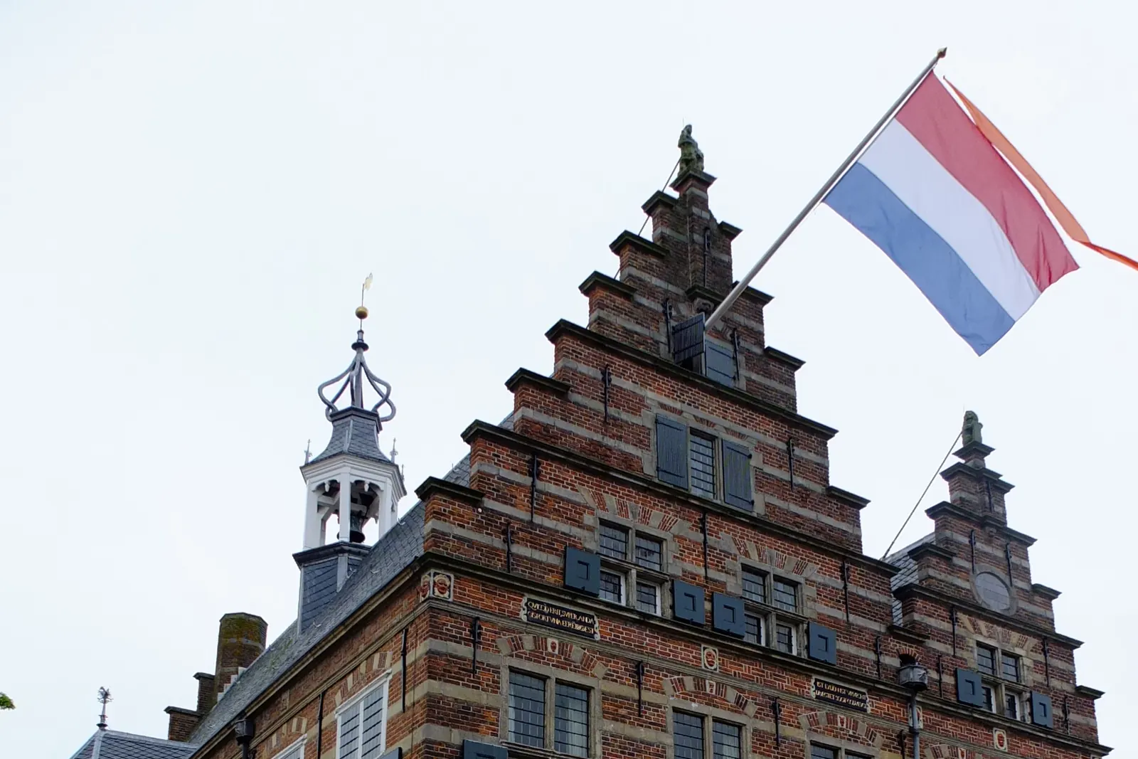 Het stadhuis van Naarden met de Nederlandse vlag en een oranje wimpel aan een mast