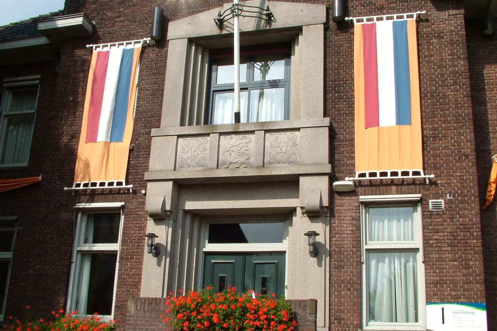 Twee banieren in de nationale kleuren met oranje aan de gevel van het gemeentehuis in Varsseveld
