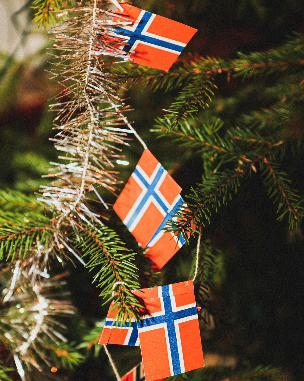 En rekke små norske papirflagg hengt opp på et juletre