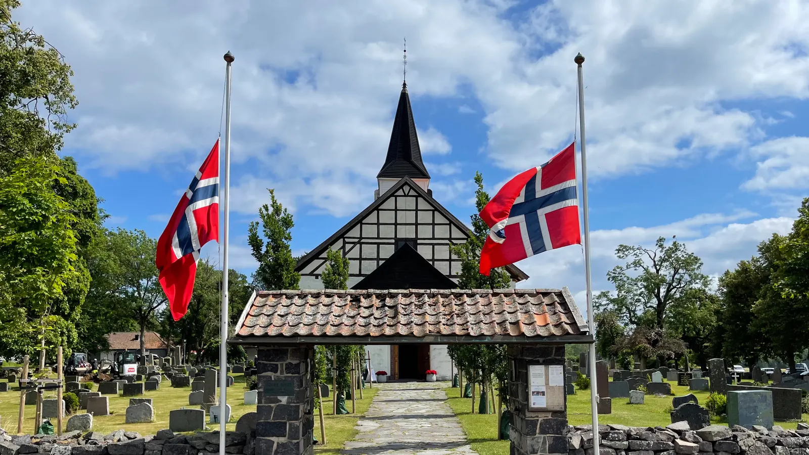 Norske flagg på halv stang ved porten til kirkegården ved Borre kirke