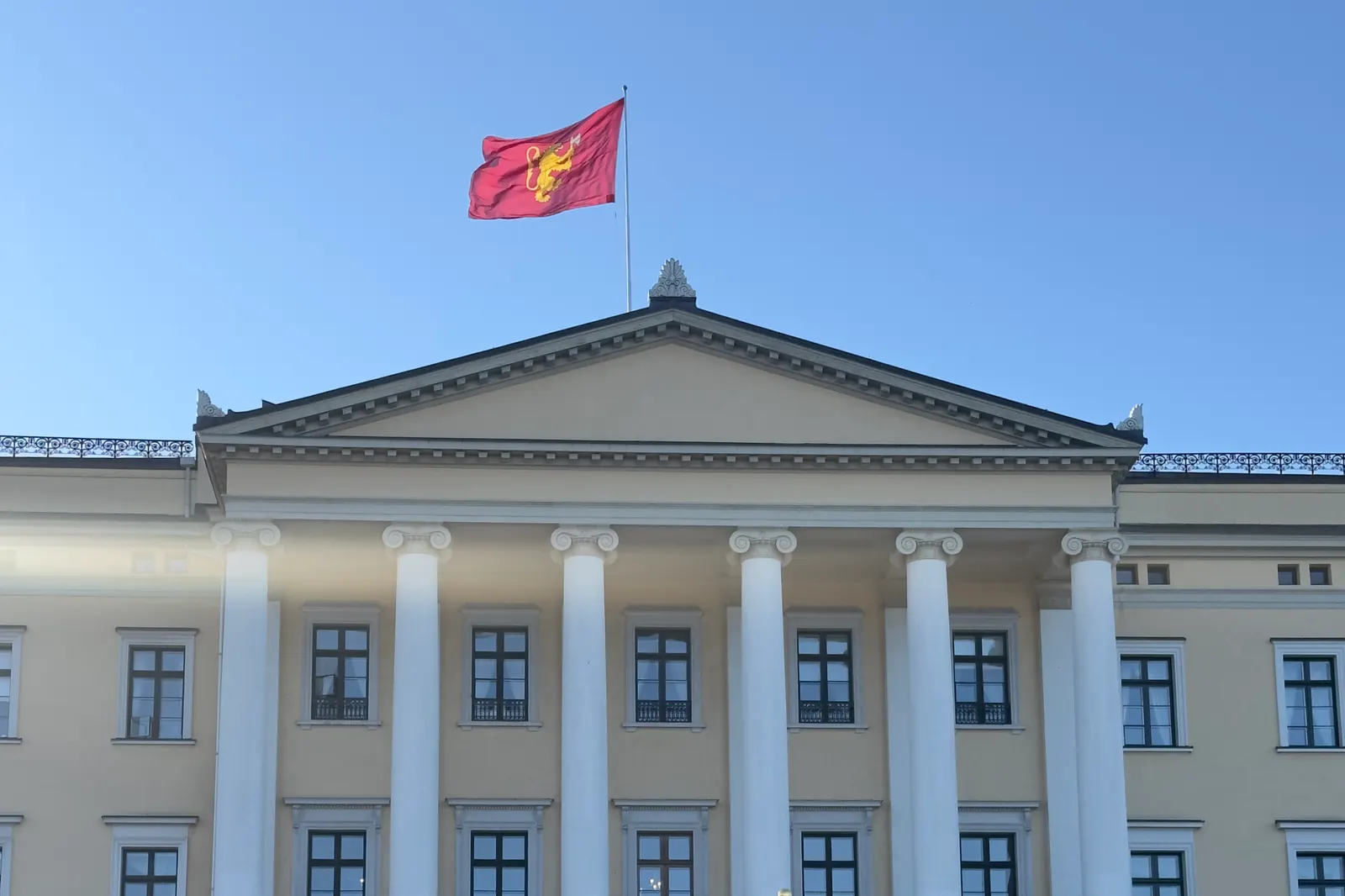 Kongeflagget med den gylne løven på rød bunn over Slottet i Oslo
