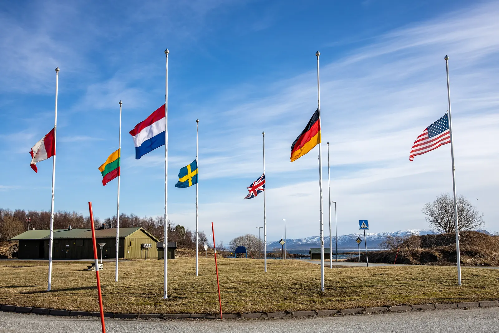 Flaggene til flere allierte land på halv stang på en åpen plass i Bodø