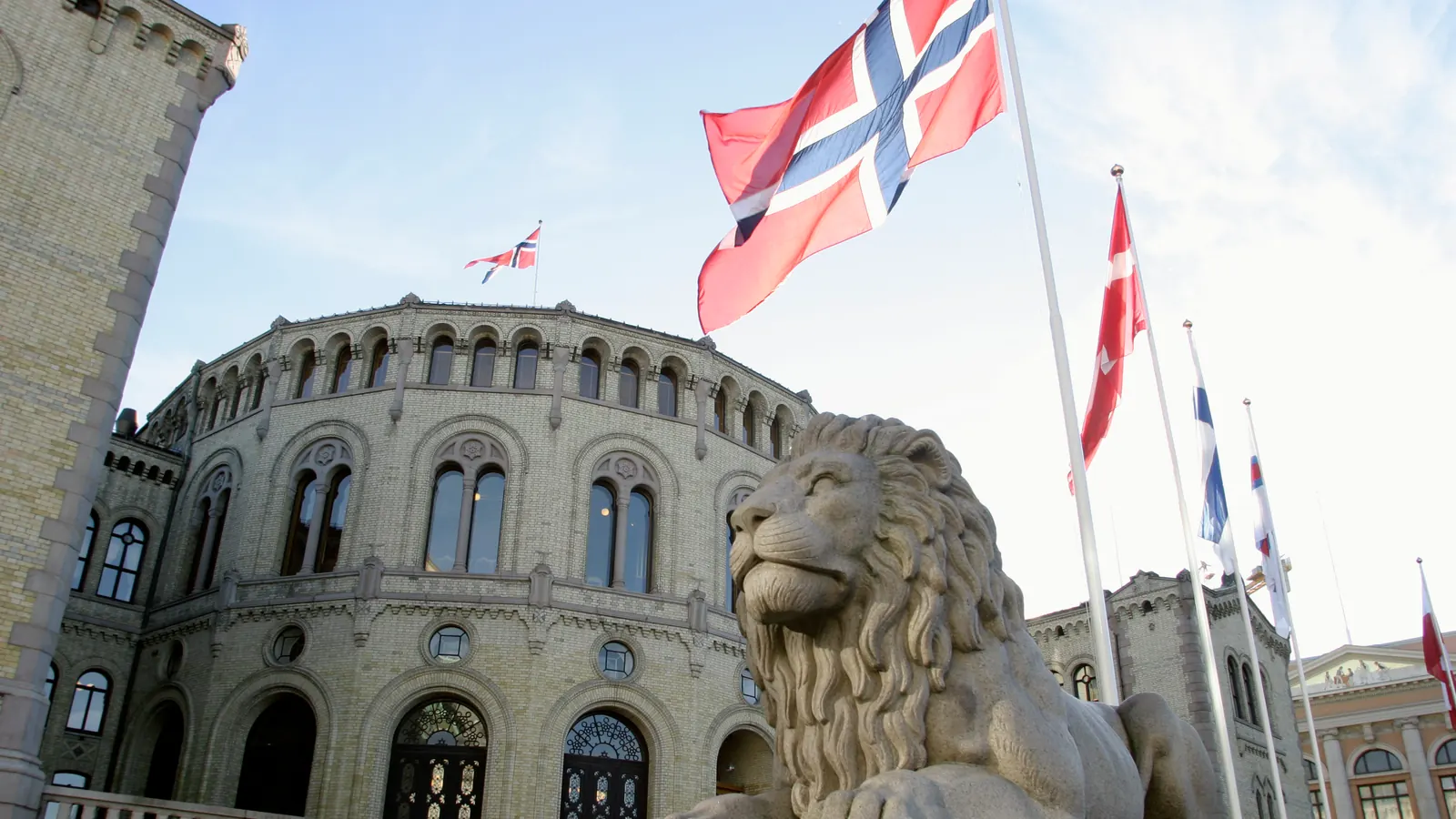 Norske og nordiske flagg på stenger foran Stortinget i Oslo
