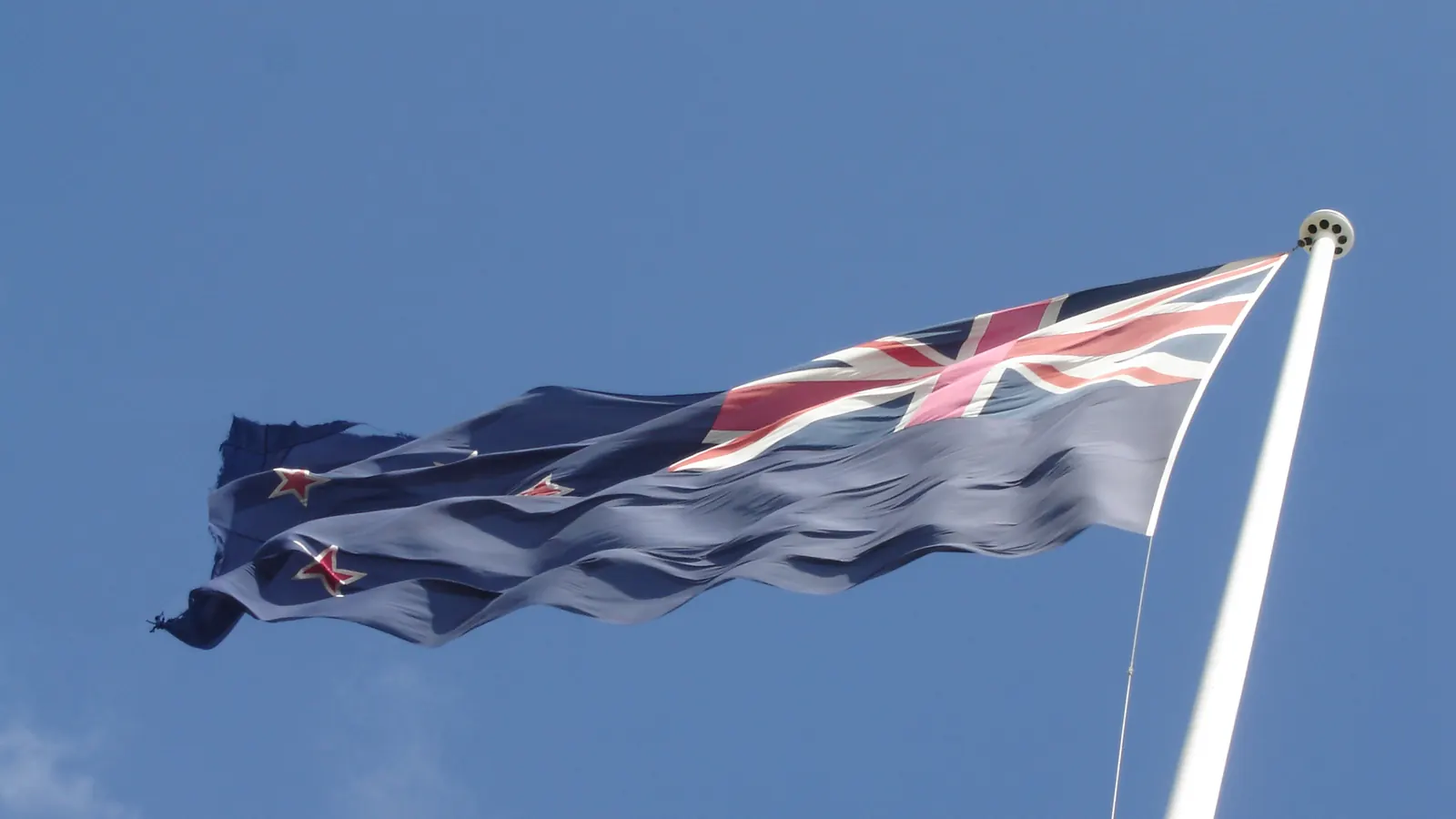 A large New Zealand flag on a tall flagpole at Auckland Airport