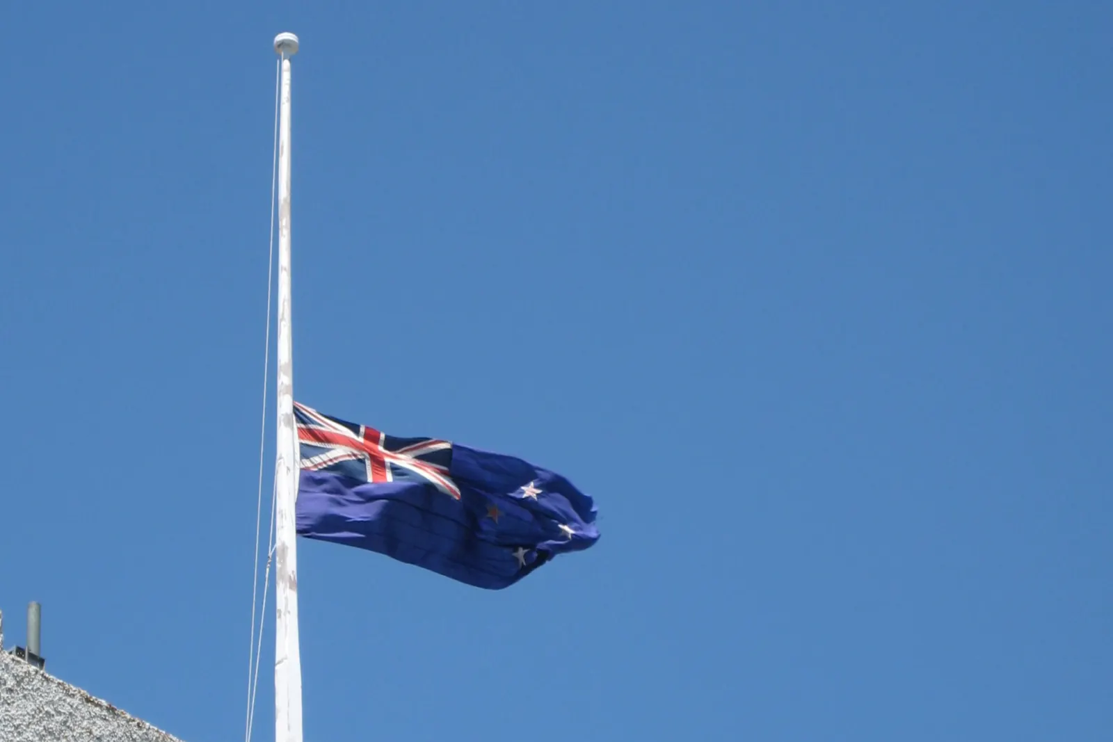 The New Zealand flag at half-mast against the sky