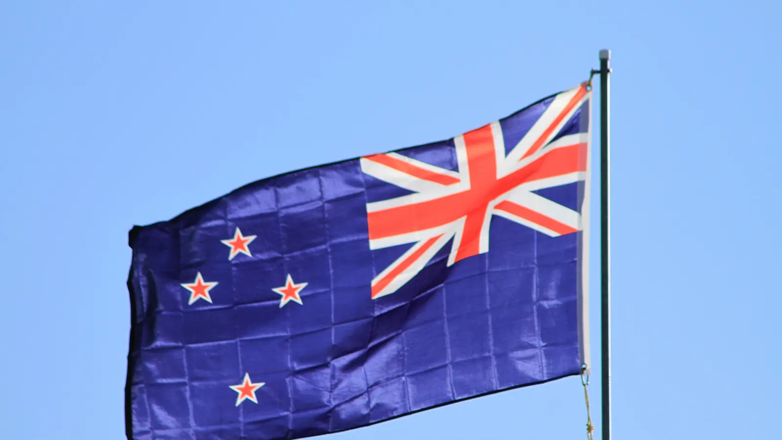 The New Zealand flag flying against a blue sky