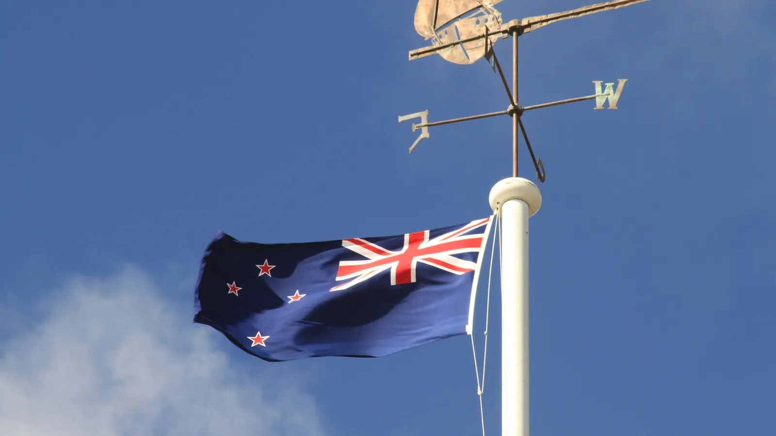 The New Zealand flag below a weathervane on a flagpole in Auckland