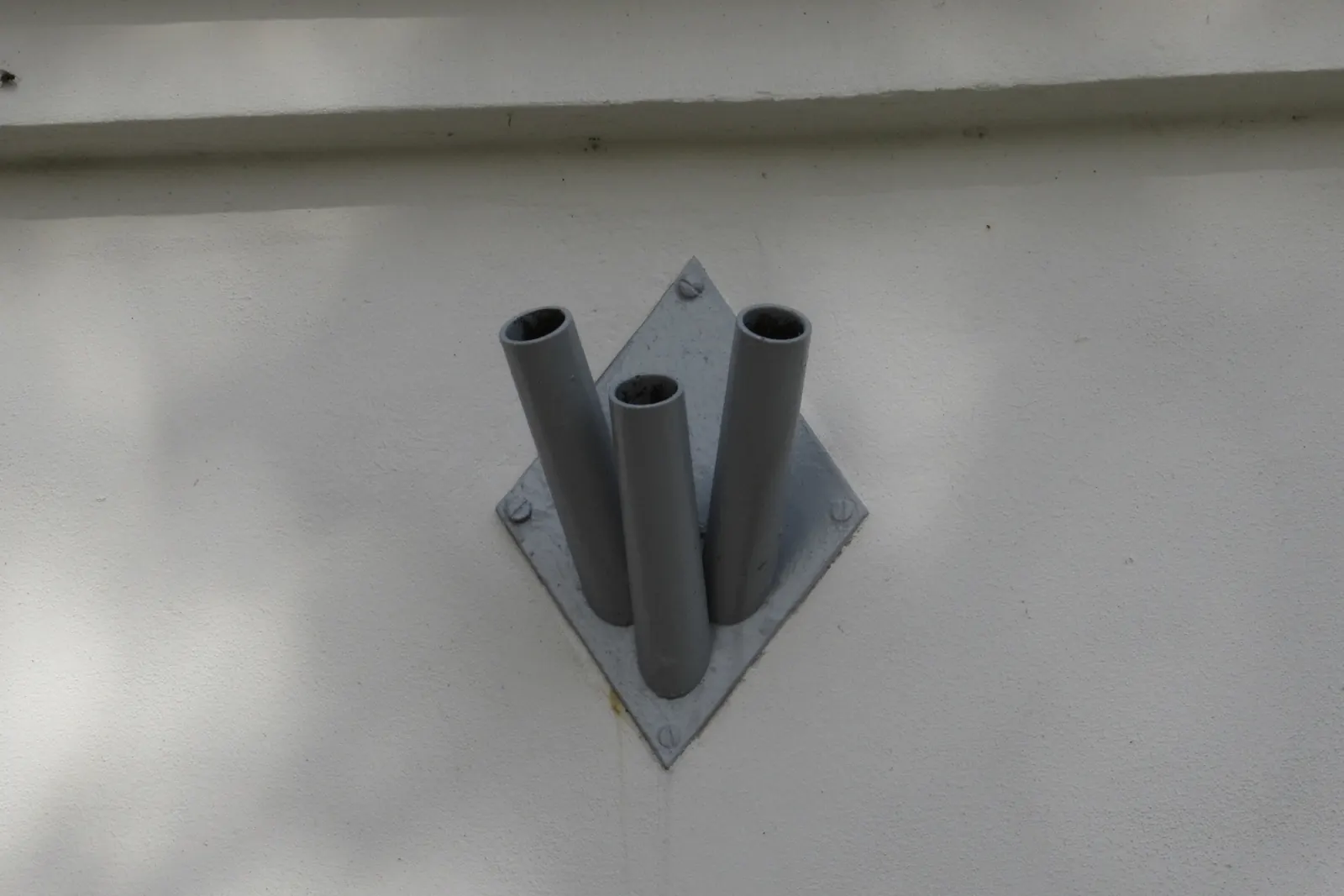 Potrójny metalowy uchwyt na drzewca flagowe na ścianie