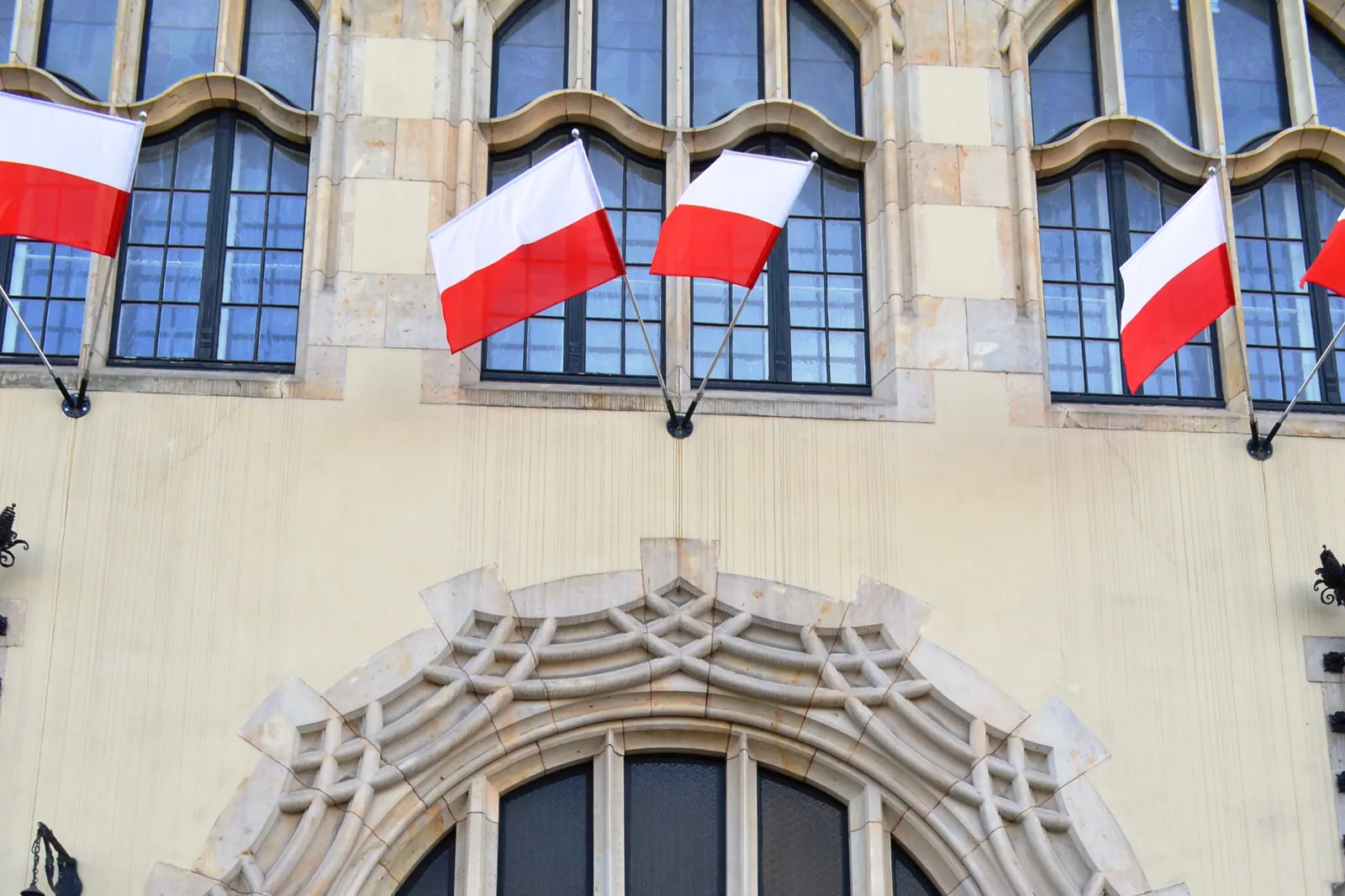 Biało-czerwone flagi w uchwytach nad bramą kamienicy w Bydgoszczy