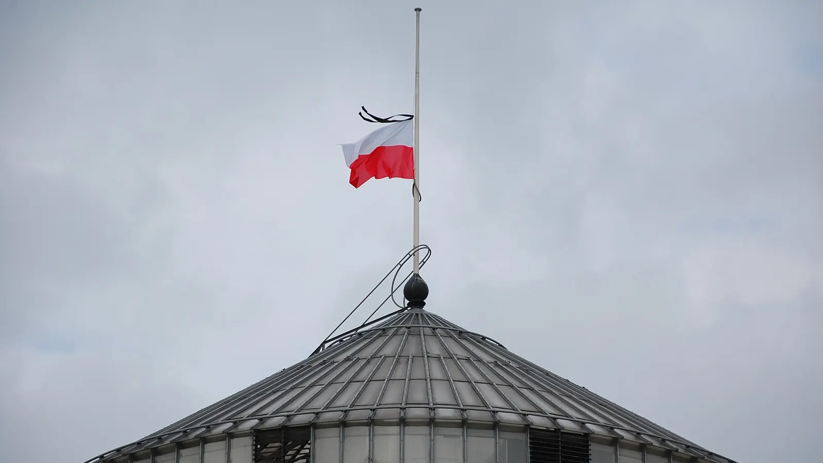 Flaga Polski z kirem opuszczona do połowy masztu na kopule Sejmu