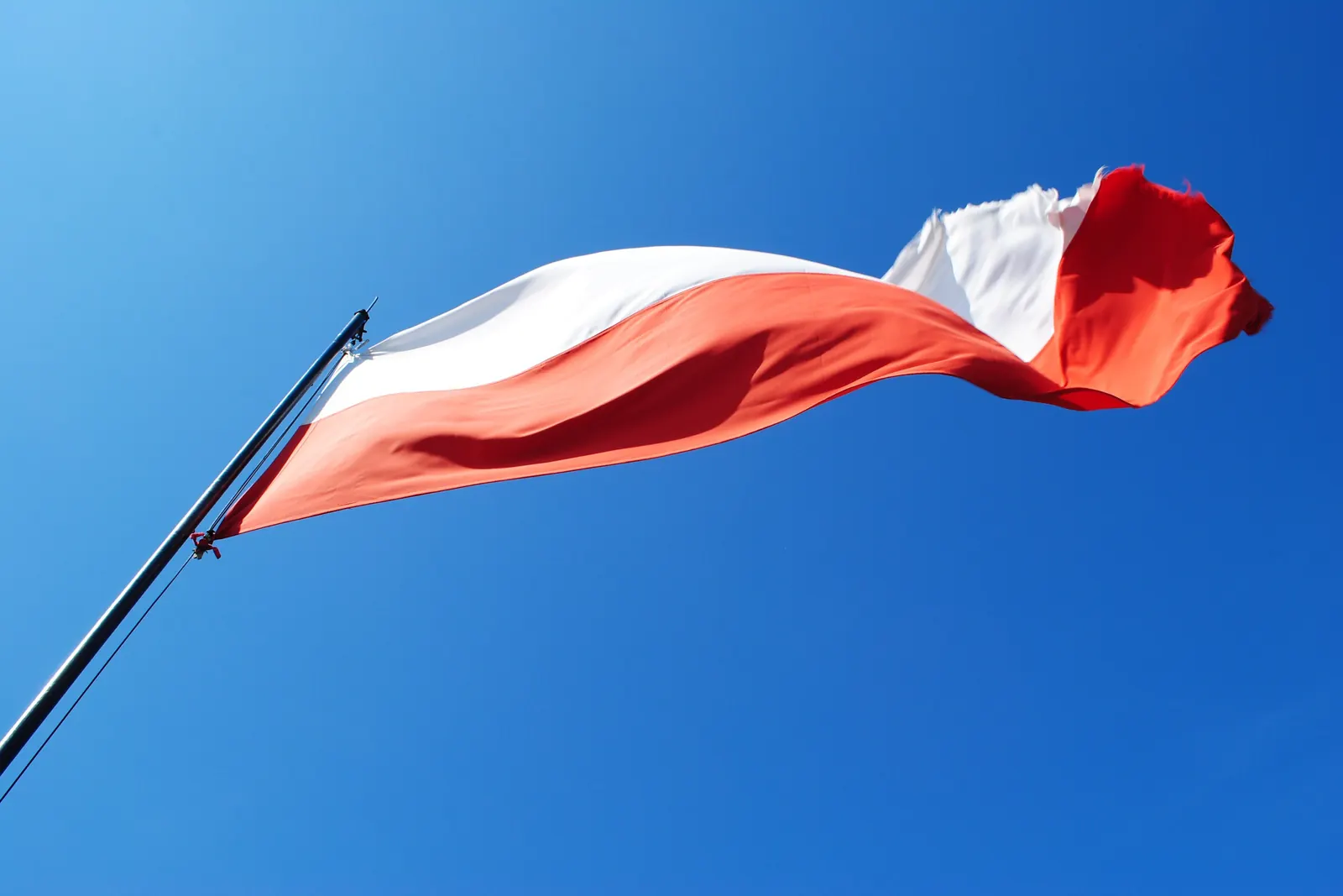 Biało-czerwona flaga na maszcie na tle ciemnobłękitnego nieba w Chęcinach