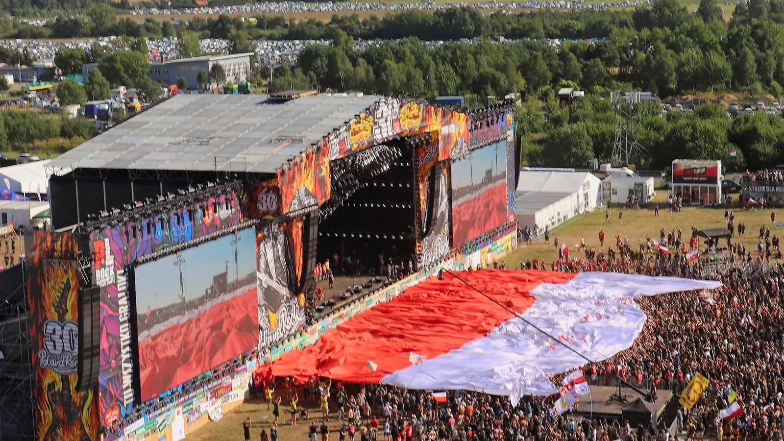 Wielka biało-czerwona flaga rozpięta nad publicznością festiwalu Pol’and’Rock w 2024 roku