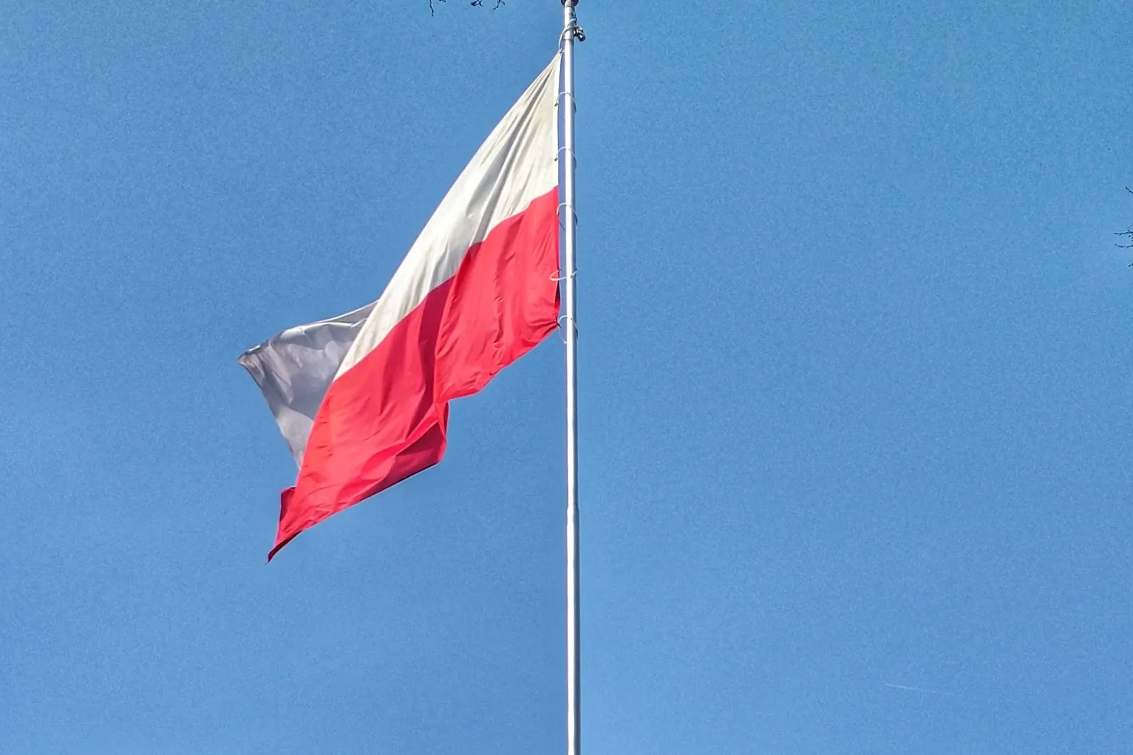 Wysoki maszt z flagą Polski przy pomniku w Jadowie