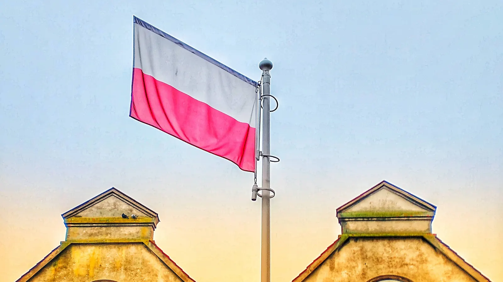 Biało-czerwona flaga na maszcie nad budynkiem w Ornecie