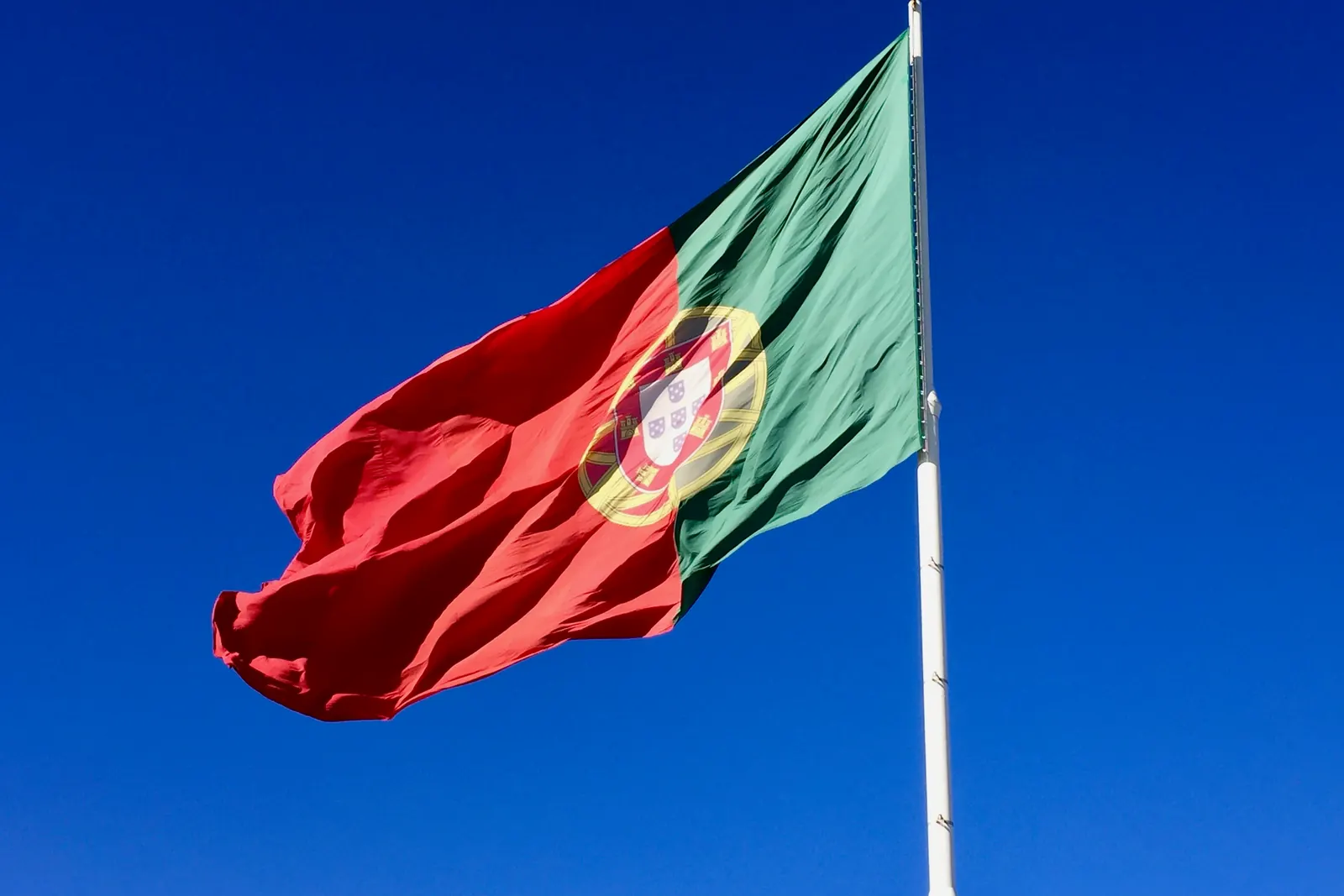 A grande Bandeira Nacional do Parque Eduardo VII desfraldada contra um céu azul intenso