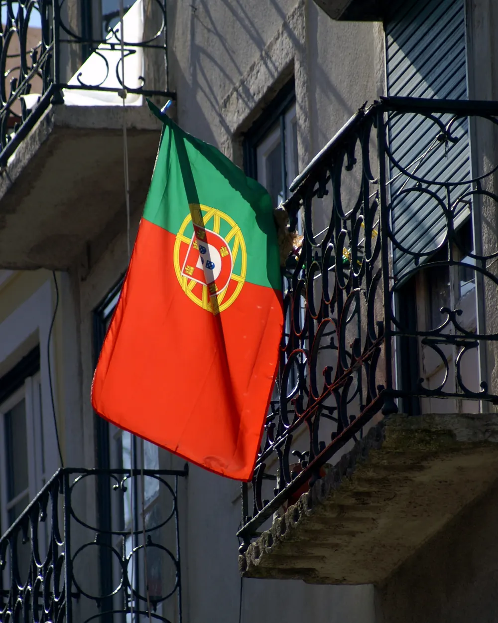 A Bandeira Nacional numa haste junto às varandas de ferro de um prédio
