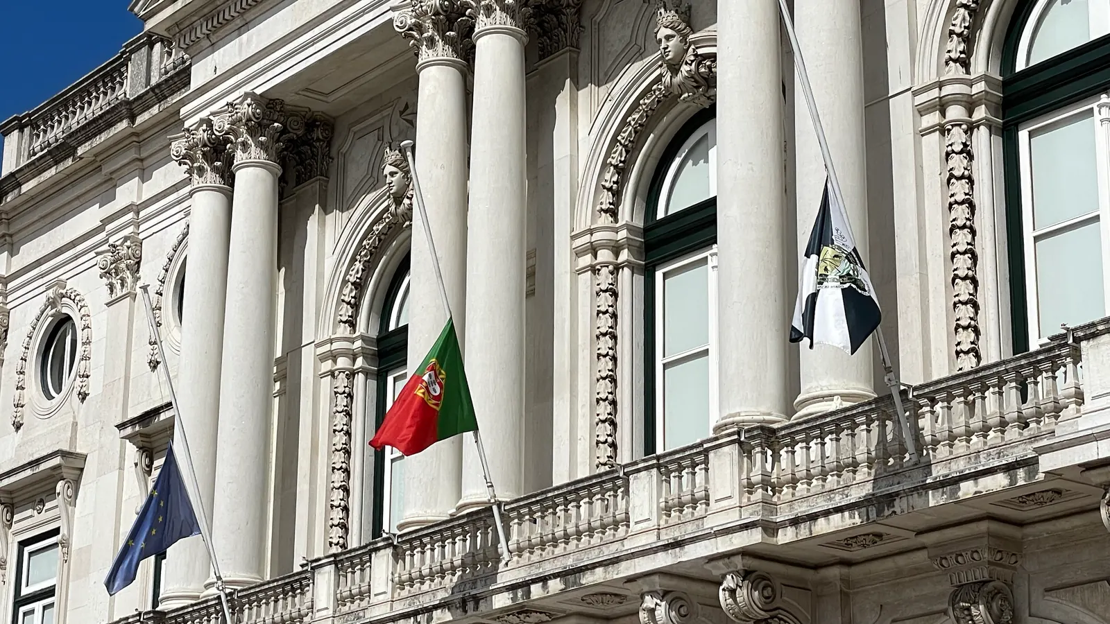 Os Paços do Concelho de Lisboa com a bandeira da União Europeia, a Bandeira Nacional ao centro e a bandeira de Lisboa, a meia haste em setembro de 2025